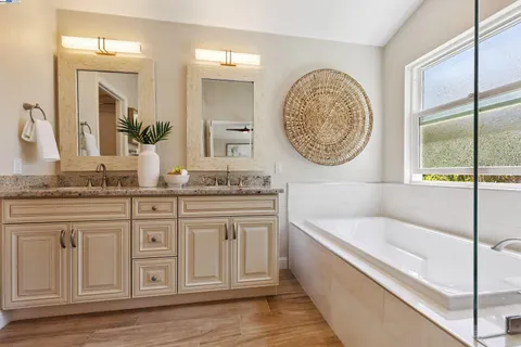 a bathroom with a granite countertop tub sink and mirror