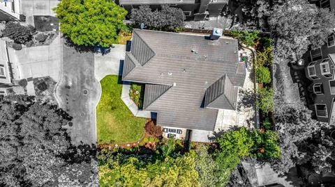 an aerial view of a house with swimming pool and large trees
