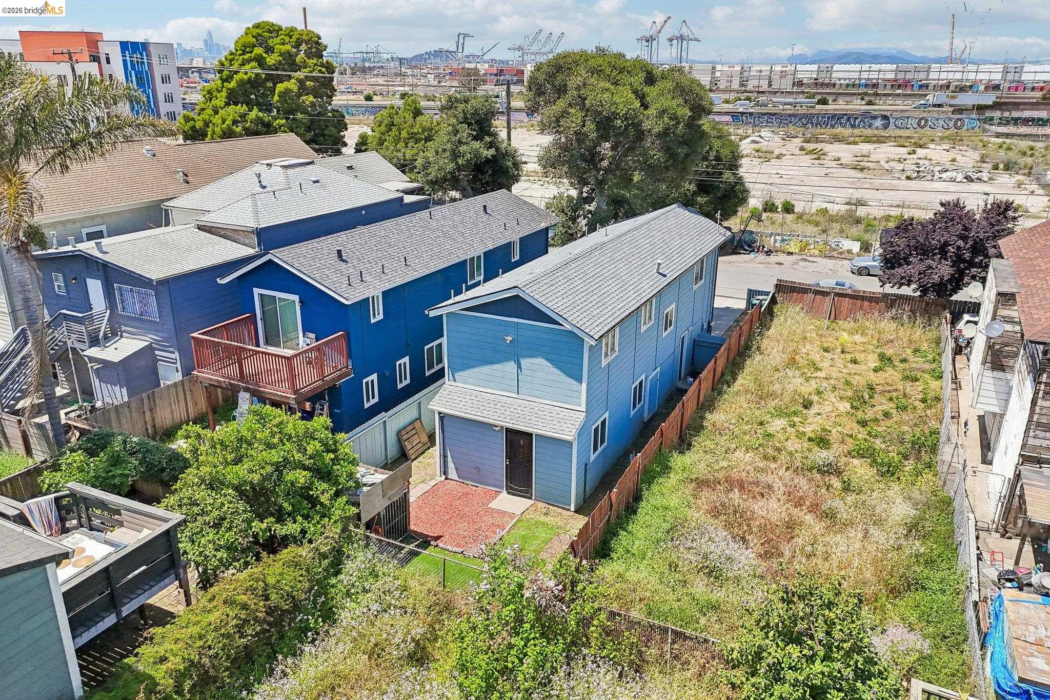 874 Pine Street Oakland, CA 94607 - Photo 36 of 39 Two-story residence featuring a light blue exterior, attached garage, and a fenced yard with mature landscaping