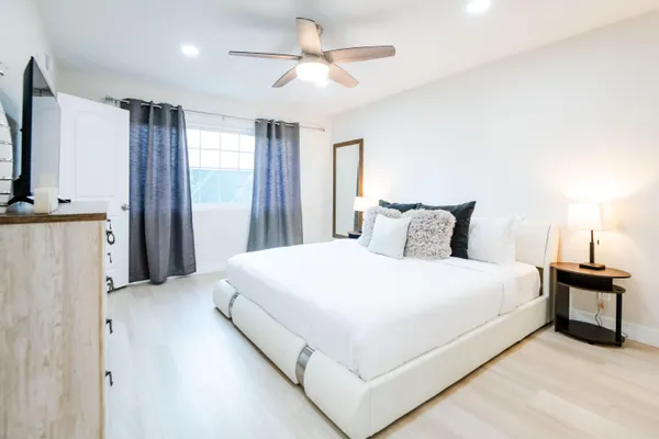 a large bed sitting in a bedroom with a flat tv screen and a chandelier