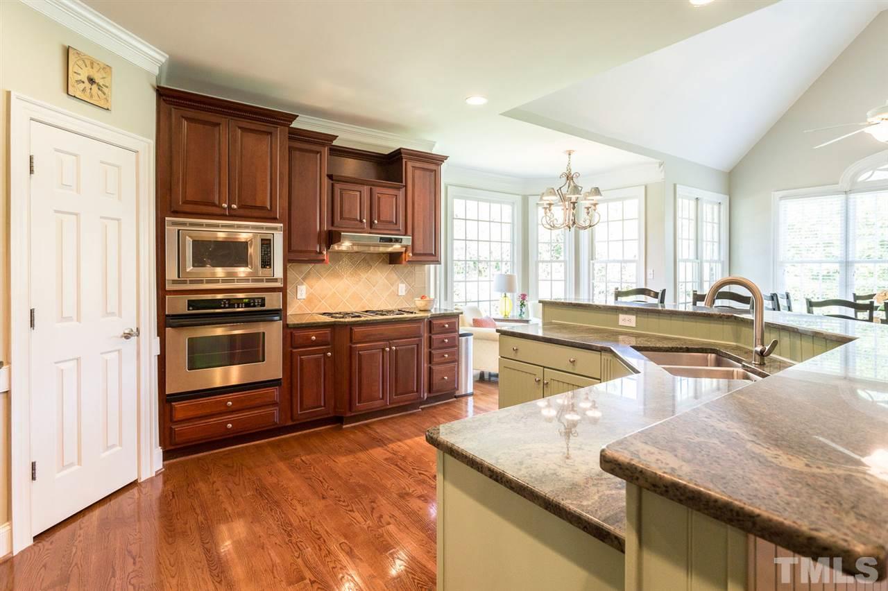 12404 Bayleaf Church Road Raleigh, NC 27614 - Photo 11 of 25 a kitchen with stainless steel appliances granite countertop a refrigerator a stove and a sink with wooden floor