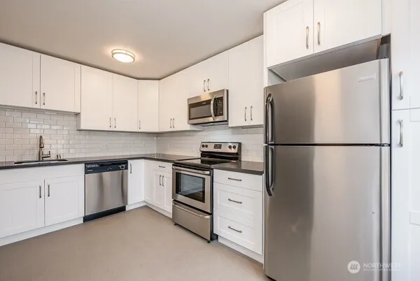 a kitchen with granite countertop white cabinets and white appliances