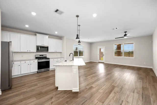 a kitchen with kitchen island white cabinets and stainless steel appliances