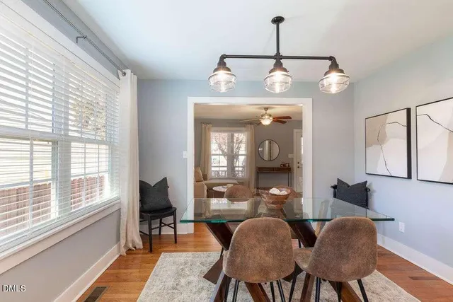 a dining room with wooden floor a chandelier a glass table and chairs