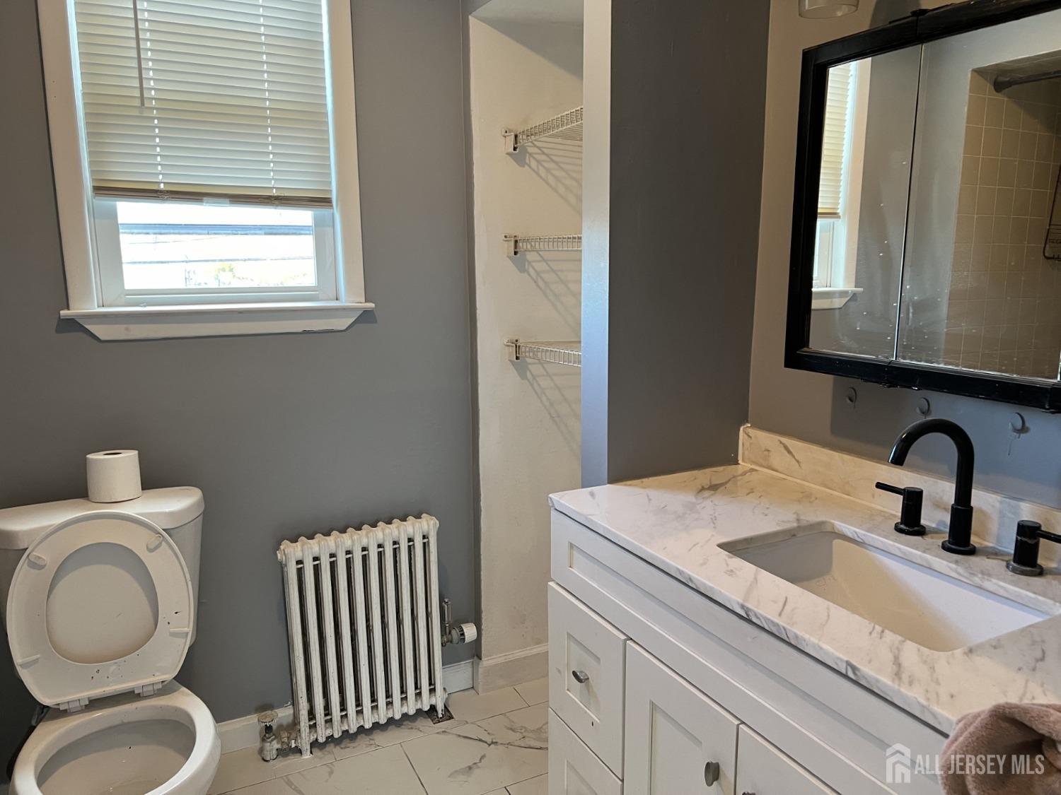 247 Washington Avenue, Unit 2F Carteret, NJ 07008 - Photo 5 of 10 a bathroom with a toilet a sink a mirror and a window