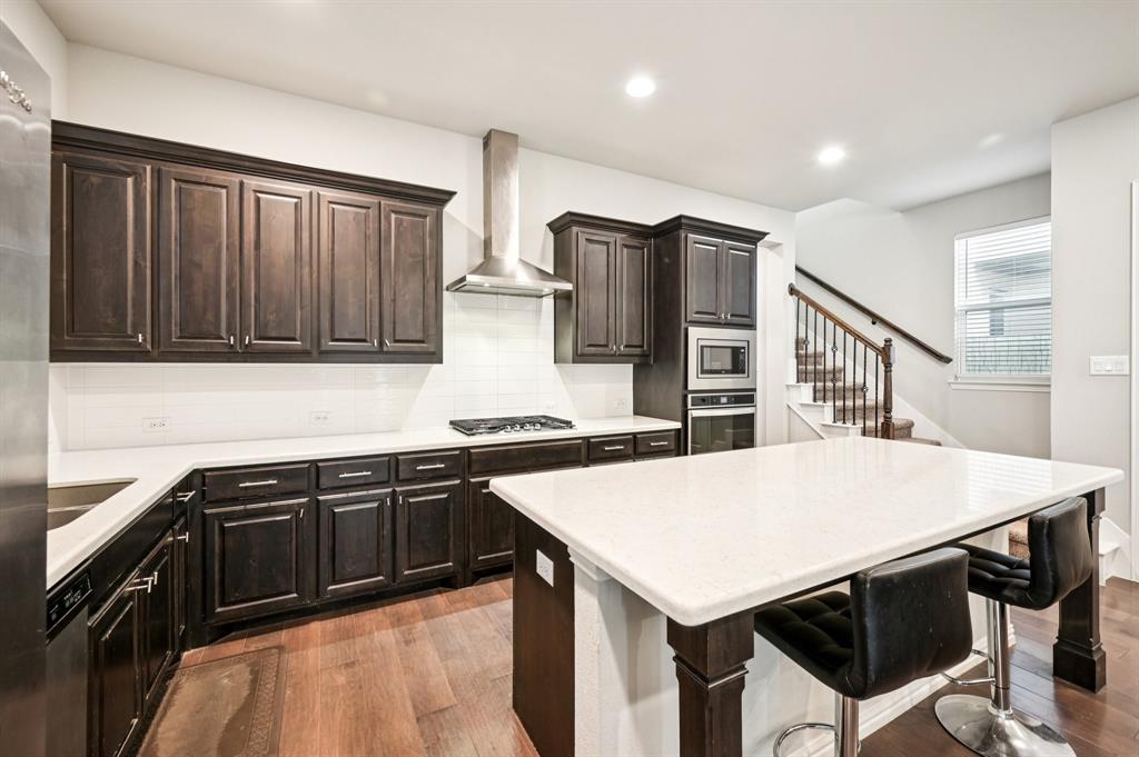 8039 Copper Way Dallas, TX 75252 - Photo 10 of 30 a kitchen with stainless steel appliances a stove a sink a microwave and wooden cabinets