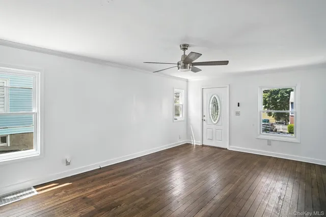 a view of an empty room with wooden floor and a window
