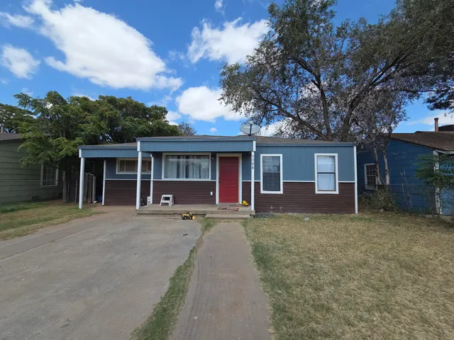 front view of a house with a garden and trees