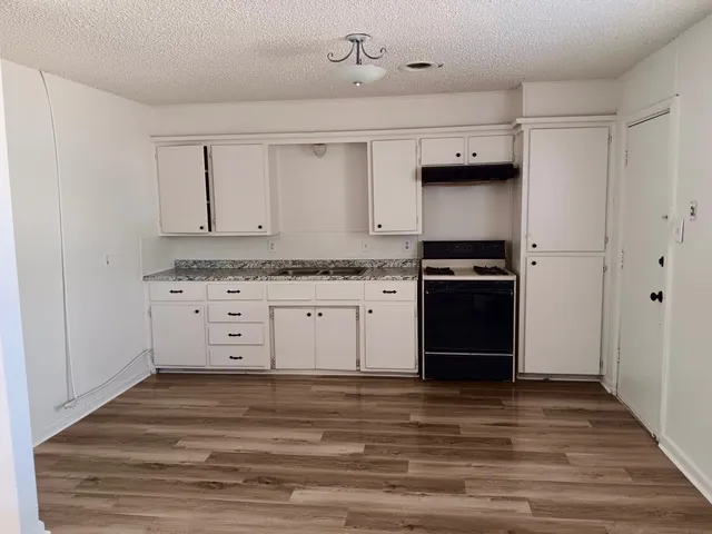 a kitchen with granite countertop a stove cabinets and wooden floor