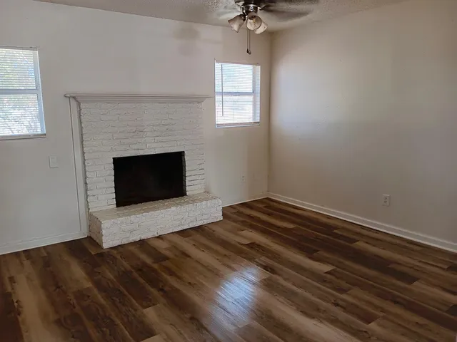 wooden floor fireplace and windows in an empty room