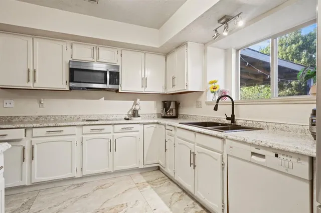 a kitchen with white cabinets sink and stainless steel appliances