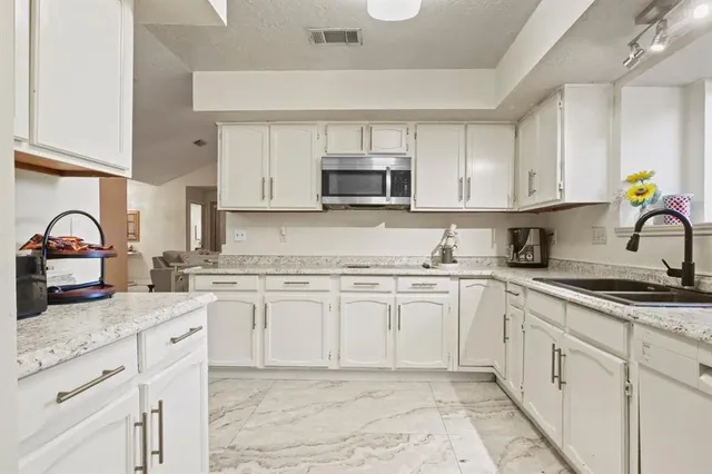 a kitchen with stainless steel appliances granite countertop a sink a stove and cabinets