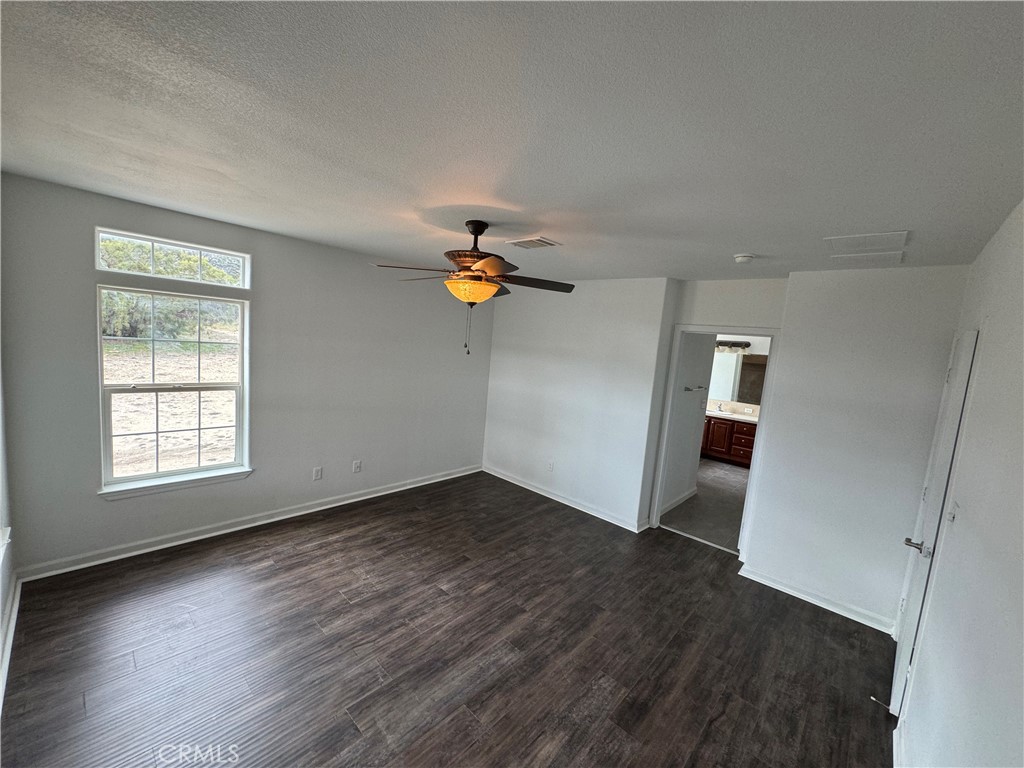 57725 Ramsey Road Anza, CA 92539 - Photo 25 of 43 an empty room with wooden floor chandelier fan and windows