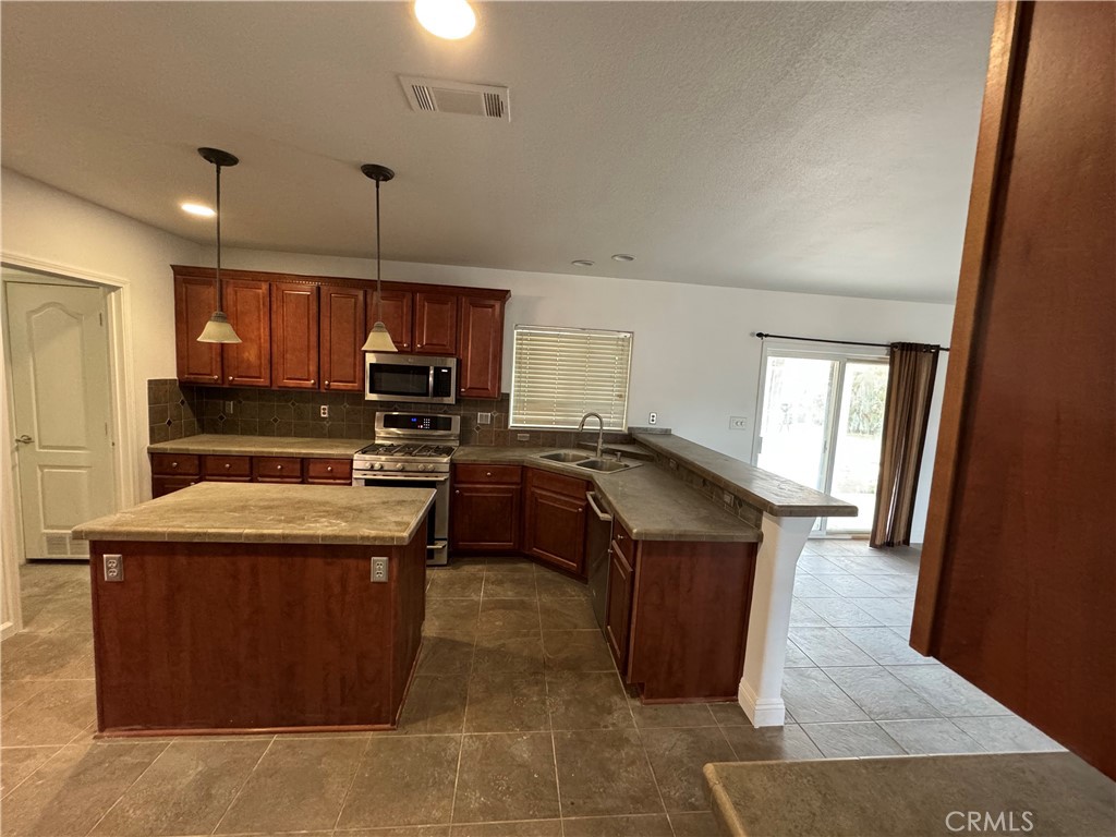 57725 Ramsey Road Anza, CA 92539 - Photo 7 of 43 a kitchen with stainless steel appliances granite countertop a stove a sink dishwasher a refrigerator and a oven with wooden floor