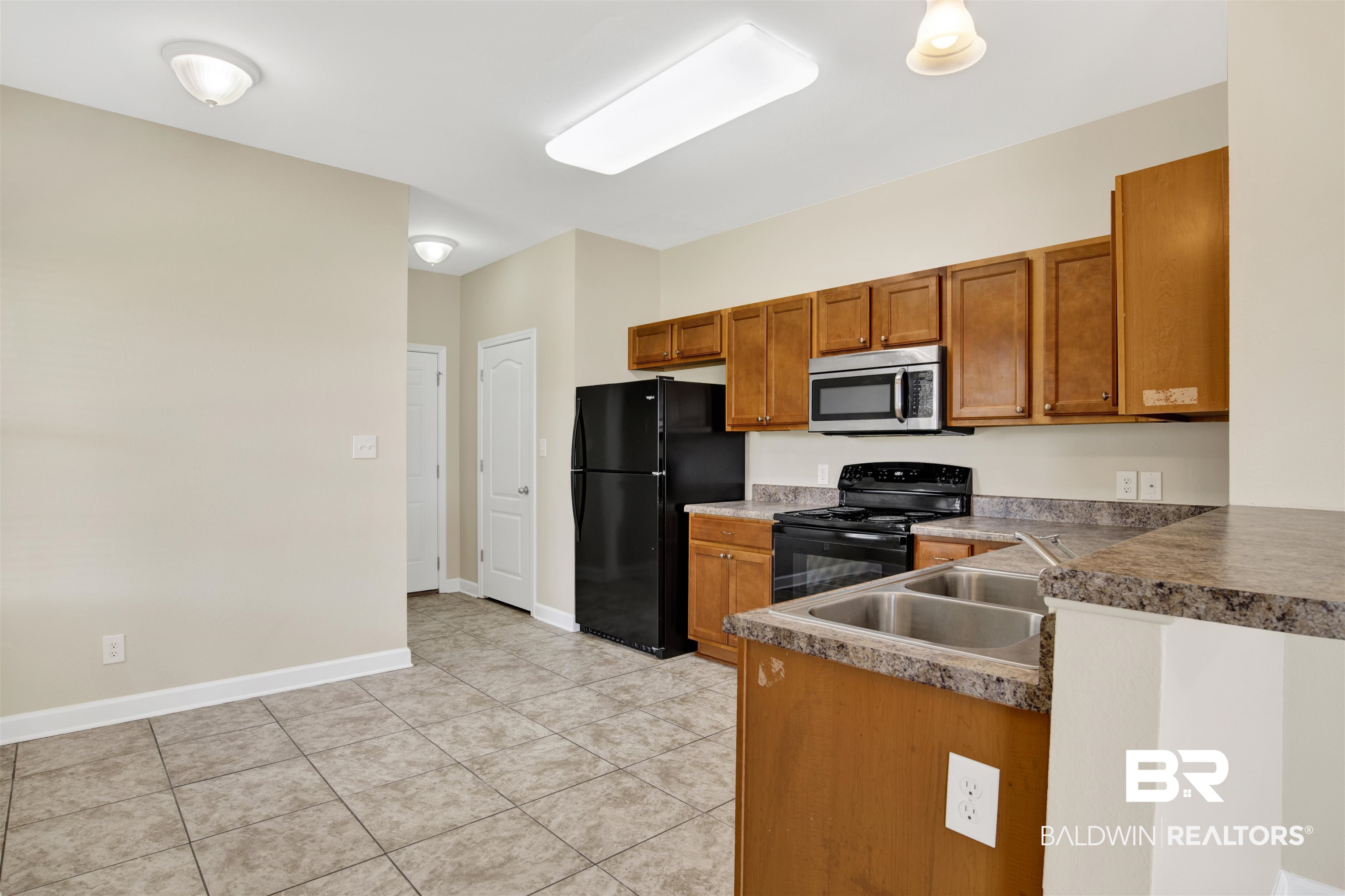2002 Shelene Way Foley, AL 36535 - Photo 7 of 23 Kitchen with brown cabinets, black appliances, a peninsula, and light tile patterned floors