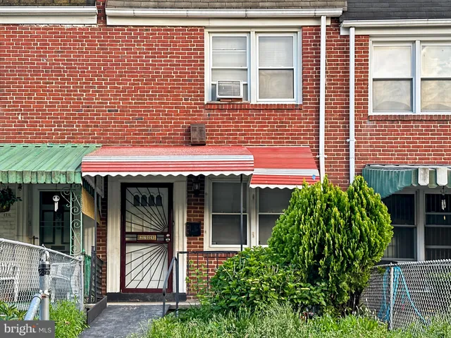 a view of brick house with a large window and potted plants