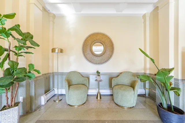 a living room with furniture a potted plant and a large window