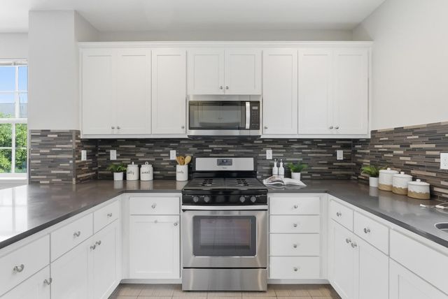 a kitchen with granite countertop white cabinets and stainless steel appliances