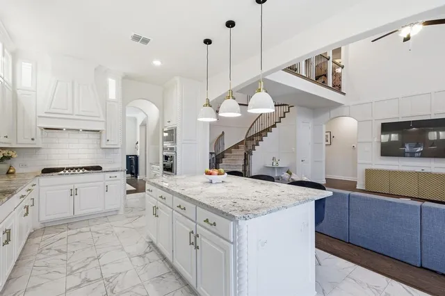 a kitchen with a stove a sink a island and chairs