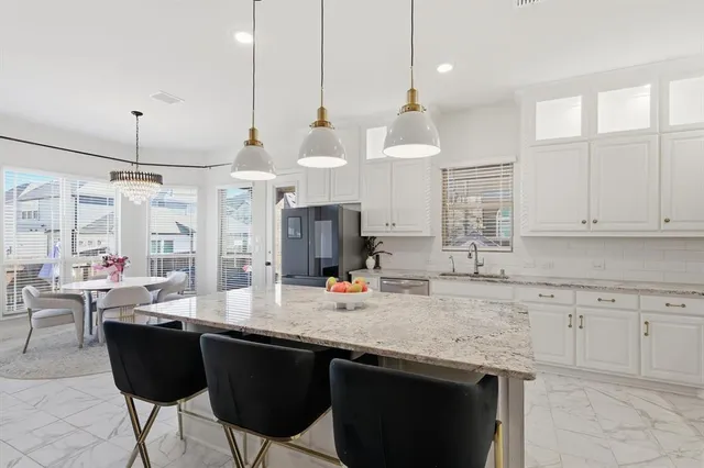 a kitchen with granite countertop a sink white cabinets and stainless steel appliances