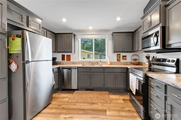 a kitchen with stainless steel appliances granite countertop a refrigerator stove a sink dishwasher and microwave