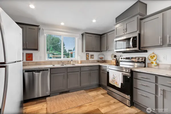 a kitchen with stainless steel appliances granite countertop a stove sink microwave and window
