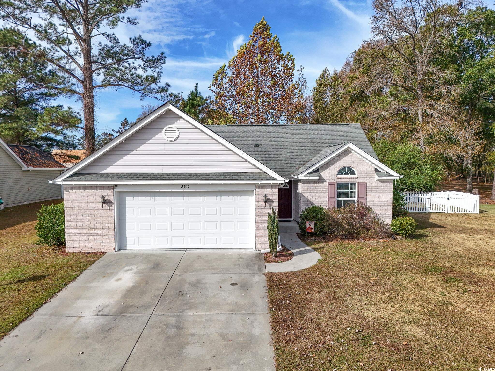 Single story home featuring driveway, a shingled roof, a garage, and brick siding