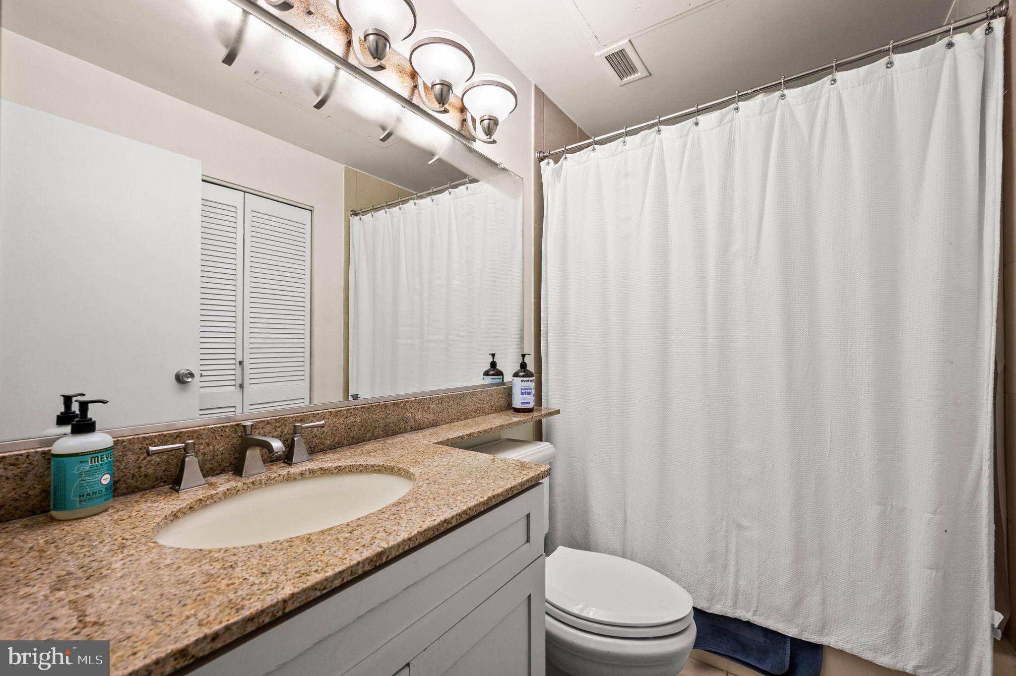 2429 Locust Street, Unit 409 Philadelphia, PA 19103 - Photo 13 of 25 a bathroom with a granite countertop sink and a mirror