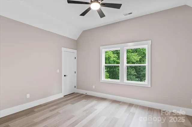 an empty room with wooden floor chandelier and windows