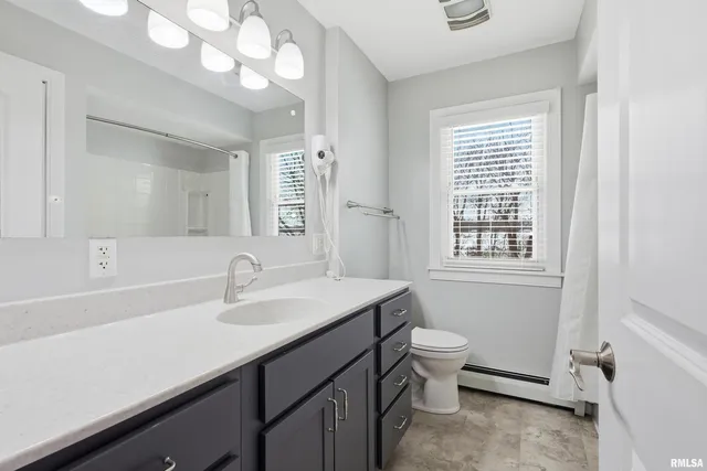 a bathroom with a sink a toilet a mirror a vanity and window