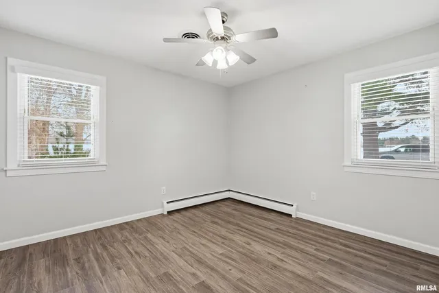 a view of an empty room with window and wooden floor