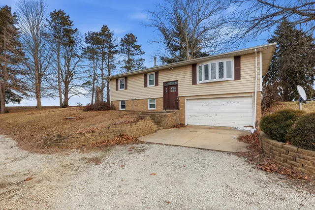 a front view of a house with a dirt yard and a large tree