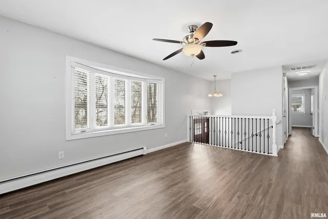 a view of empty room with wooden floor and fan