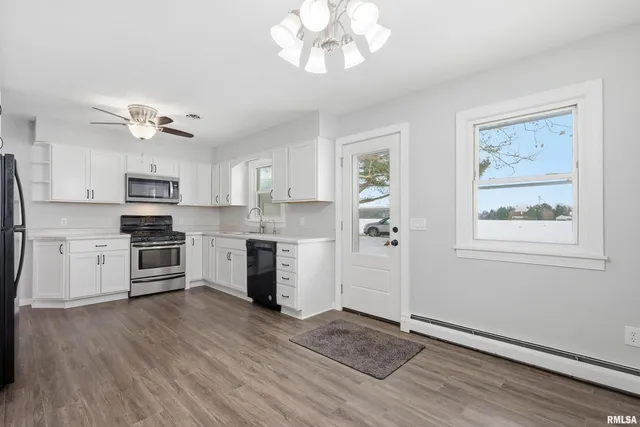a kitchen with stainless steel appliances cabinets a wooden floor and a window