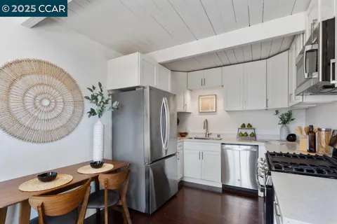 a kitchen with stainless steel appliances granite countertop a refrigerator a stove a sink dishwasher and white countertops with wooden floor