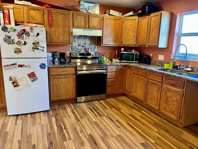 a kitchen with stainless steel appliances granite countertop a stove a sink and a refrigerator