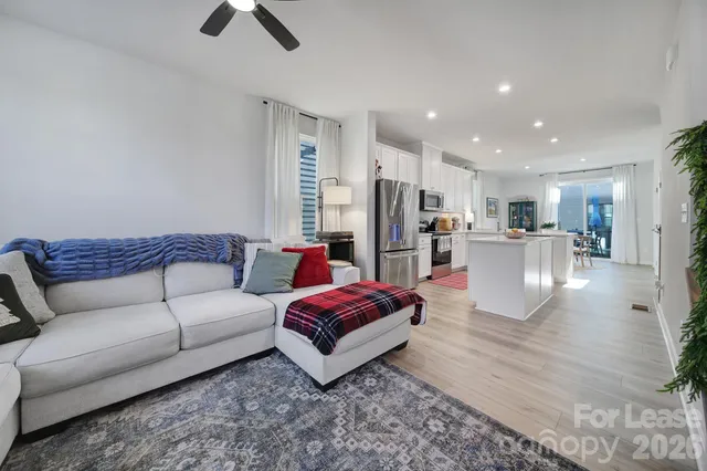 a living room with furniture wooden floor and a kitchen view