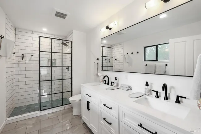 a bathroom with a double vanity sink toilet and shower