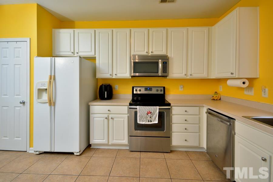 8249 City Loft Court Raleigh, NC 27613 - Photo 9 of 28 a kitchen with white cabinets and stainless steel appliances