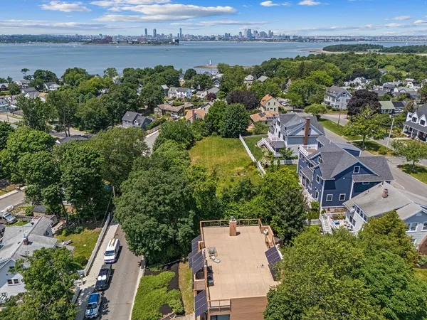 an aerial view of a city with lots of residential buildings ocean and mountain view in back