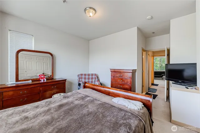 a bedroom with a bed and a flat tv screen on dresser
