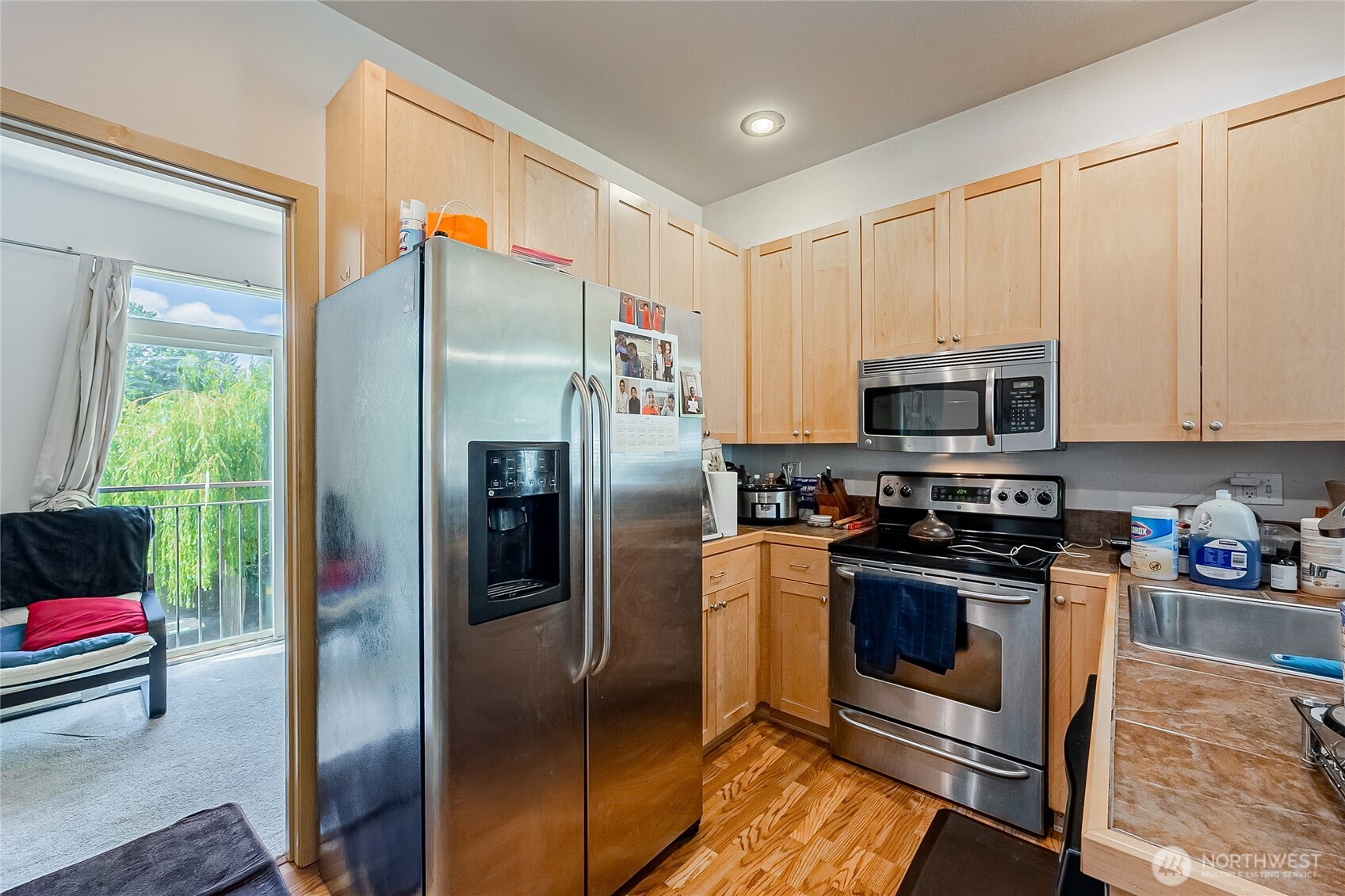 13005 64th Avenue South, Unit B117 Seattle, WA 98178 - Photo 10 of 37 a kitchen with stainless steel appliances granite countertop a refrigerator a stove and a sink with wooden floor