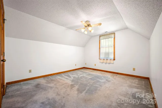 an empty room with a chandelier fan and windows