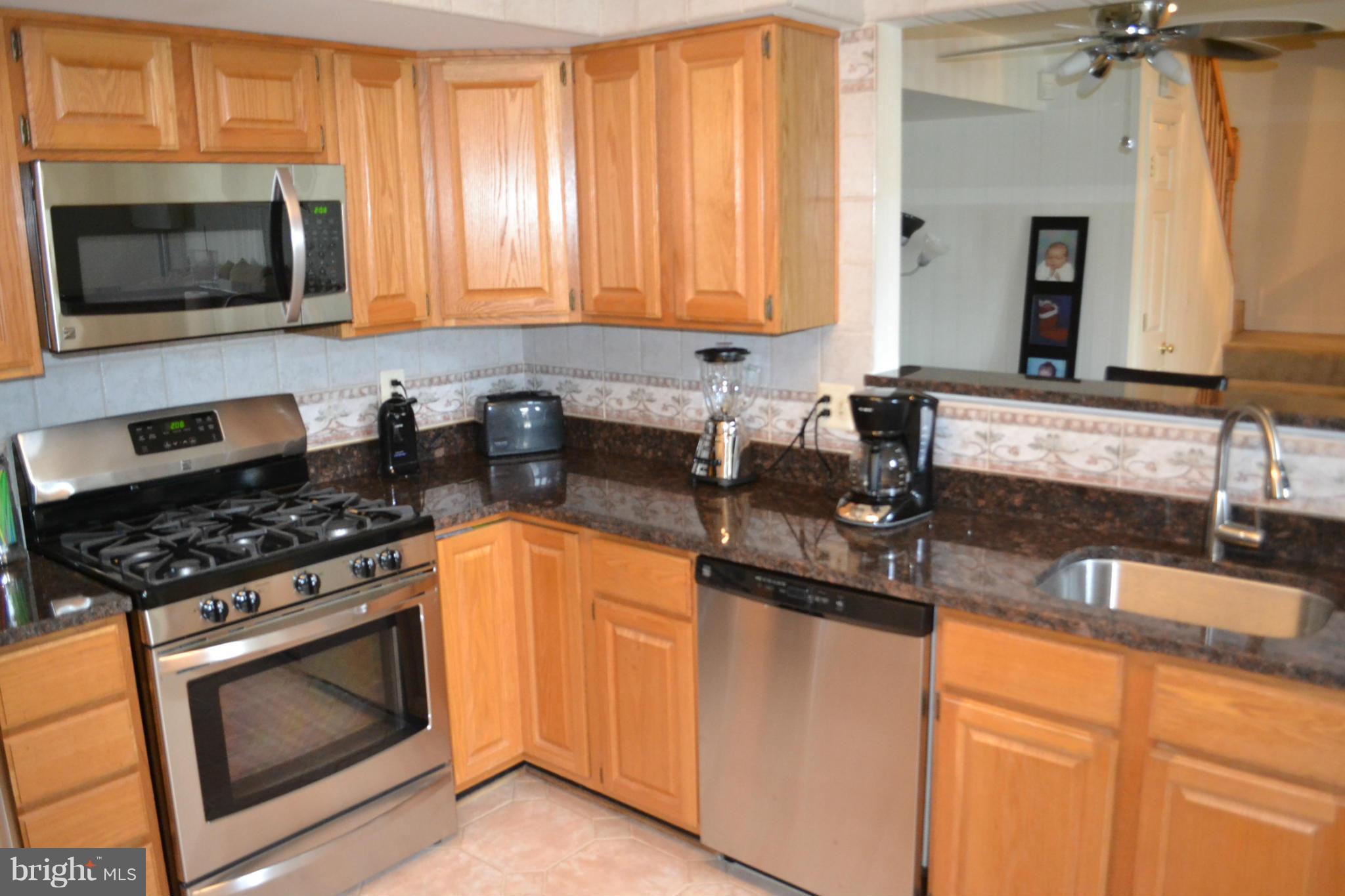 17045 Islip Loop, Unit 301 Dumfries, VA 22026 - Photo 2 of 14 a kitchen with granite countertop a sink a stove and microwave