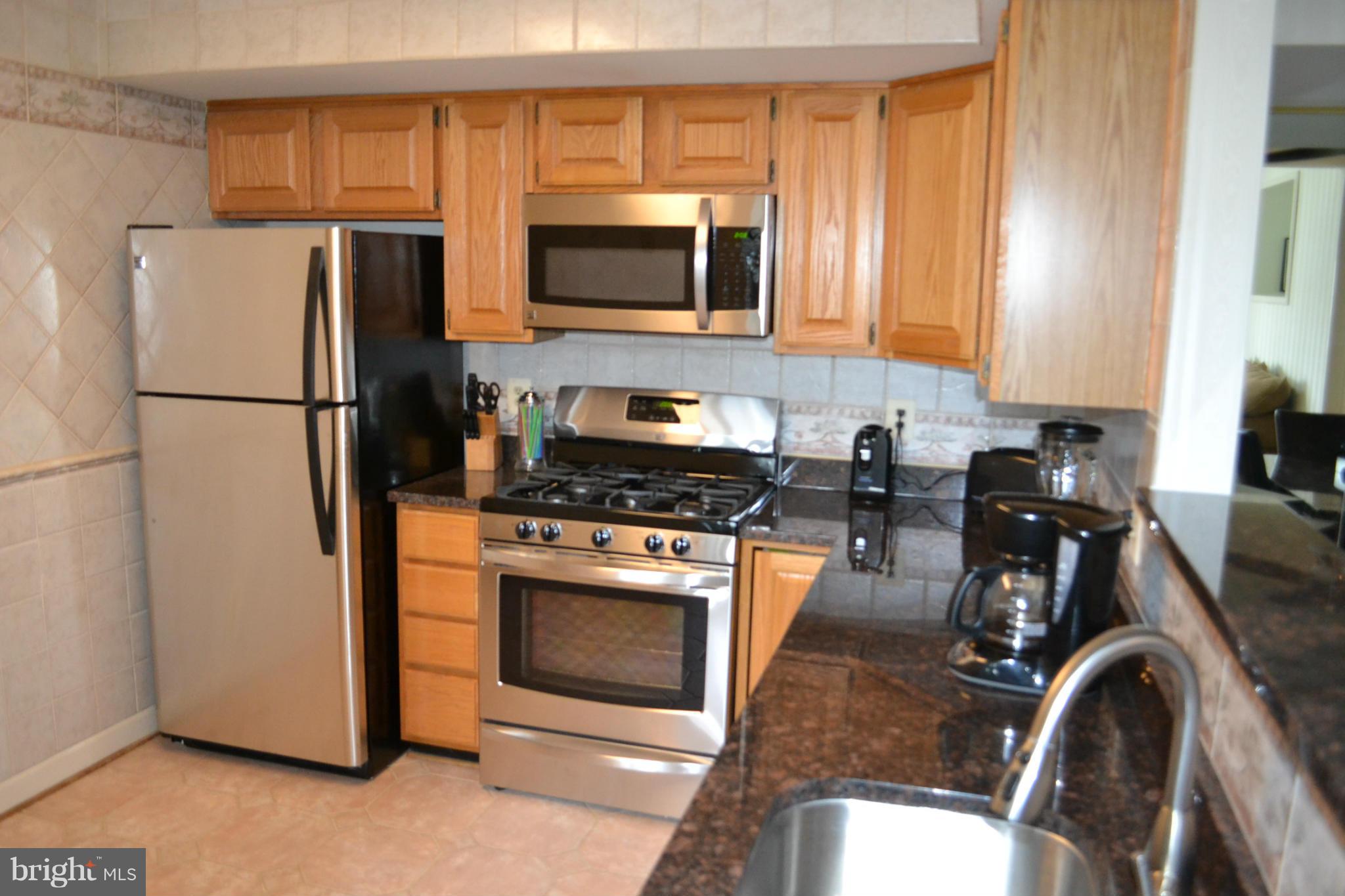 17045 Islip Loop, Unit 301 Dumfries, VA 22026 - Photo 3 of 14 a kitchen with stainless steel appliances granite countertop a refrigerator stove top oven a sink and dishwasher