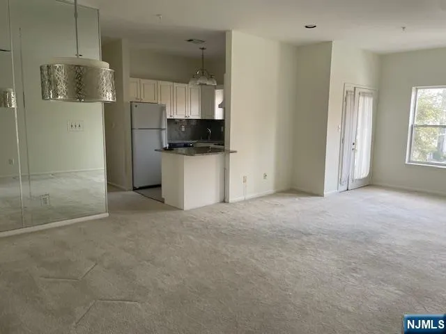 a view of empty room with a kitchen and a refrigerator
