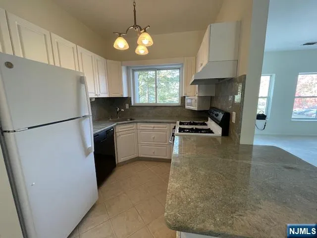 a kitchen with a refrigerator a sink and white cabinets