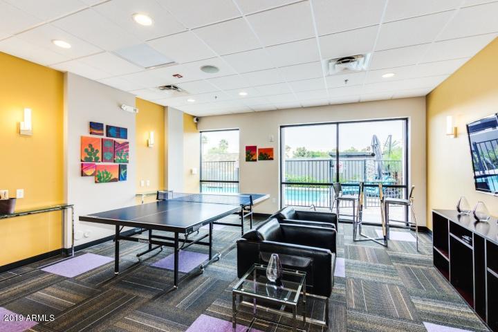 535 West Thomas Road, Unit 211 Phoenix, AZ 85013 - Photo 18 of 24 a living room with furniture a flat screen tv and a floor to ceiling window