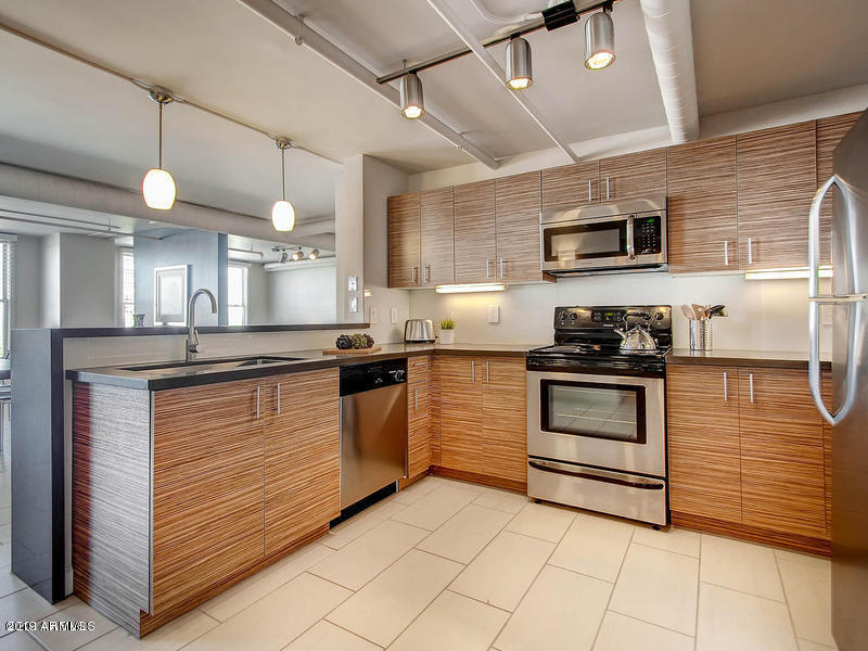 535 West Thomas Road, Unit 211 Phoenix, AZ 85013 - Photo 3 of 24 a kitchen with stainless steel appliances kitchen island granite countertop a stove a sink and a microwave