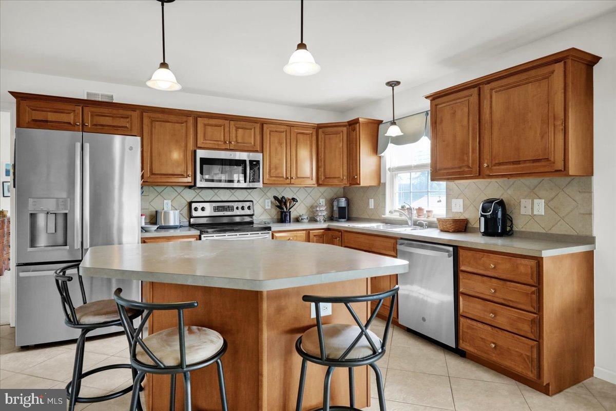 2509 Joshua Drive Sinking Spring, PA 19608 - Photo 5 of 35 a kitchen with stainless steel appliances granite countertop a stove a sink a microwave a refrigerator a dining table and chairs with wooden floor